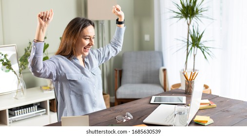 Young woman holding hands up yelling looking at screen of laptop celebrating achievement successfully completed job project presentation