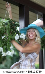 Young Woman Holding A Hanging Flower Basket And Smiling