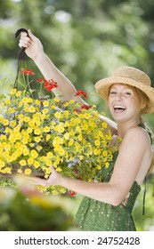 Young Woman Holding A Hanging Flower Basket And Smiling