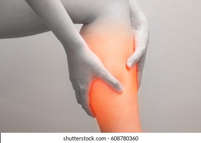 Young woman holding her calf muscle in pain with red highlighted, Isolated on white background