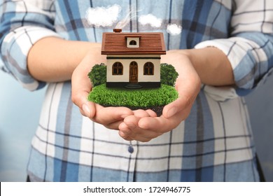 Young woman holding her dream house with beautiful green lawn, closeup