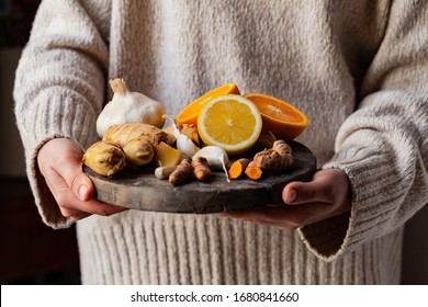 Young woman in holding in her hands immunity strengthening kit: ginger, lemon, orange, garlic, turmeric. Anti virus natural organic products. Healthcare, home remedy against cold, influenza. Closeup - Powered by Shutterstock