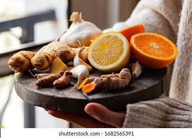 Young woman in holding in her hands immunity strengthening kit: ginger, lemon, orange, garlic, turmeric. Anti virus natural organic products. Healthcare, home remedy against cold, influenza. Closeup - Powered by Shutterstock