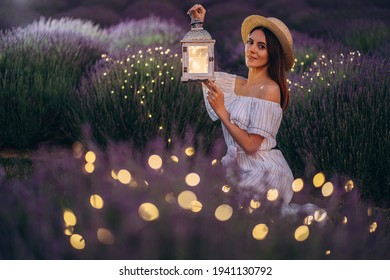 Young Woman Holding Lantern In The Lavender Field During Night. High Quality Photo