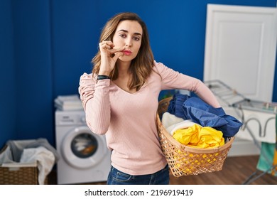 Young Woman Holding Laundry Basket Mouth And Lips Shut As Zip With Fingers. Secret And Silent, Taboo Talking 