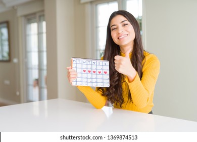 Young Woman Holding Menstruation Calendar Happy With Big Smile Doing Ok Sign, Thumb Up With Fingers, Excellent Sign