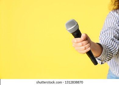 Young woman holding microphone in hand on color background. Space for text