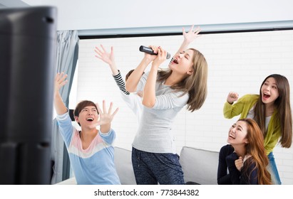 Young Woman Holding Microphone And Singing At Karaoke
