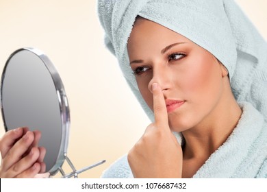 Young Woman Holding Mirror And Touching Her Nose