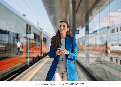 Young Woman Holding Mobile In A Train Station. Commuting To Work. Public Transport Concept.