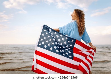 Young woman holding national American flag walking ocean beach. America Independence Day concept. 4th of July. - Powered by Shutterstock