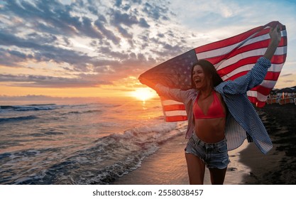 Young woman holding national American flag walking ocean beach. America Independence Day concept - Powered by Shutterstock