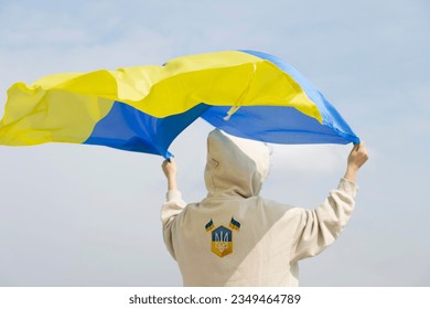 Young woman holding national flag of Ukraine over her head against blue sky. Support, Save, Help, Pray for Ukraine. ukrainian independence day celebration August 24 - Shutterstock ID 2349464789