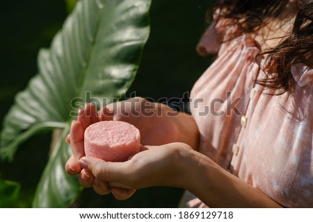 Young woman holding natural eco friendly solid shampoo bar, conditioner or soap. Zero waste and sustainable plastic free lifestyle concept