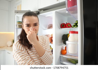 Young Woman Holding Nose Cause Of Bad Smell In Refrigerator In Kitchen