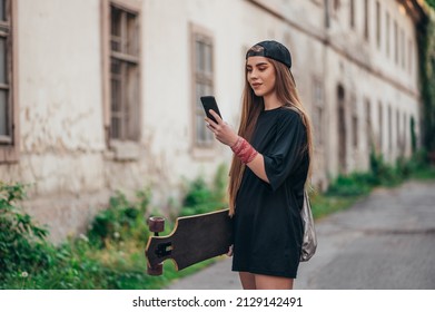 Young woman holding on her longobard and using a smartphone while walking on the road - Powered by Shutterstock