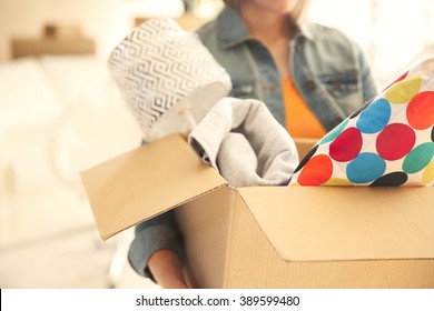 Young woman holding open cardboard box with things for moving into new house