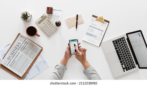 
Young woman holding phone and doing numbers while managing her business.