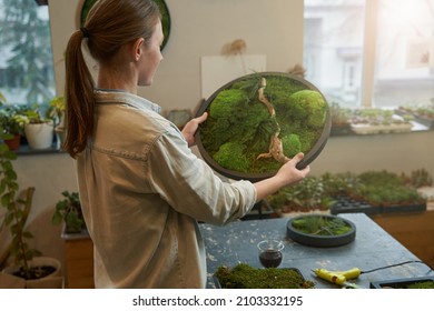 Young woman holding picture with green moss