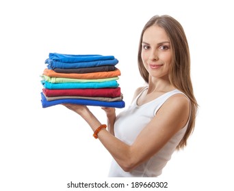 Young Woman Holding A Pile Of Clothes, Isolated On White Background