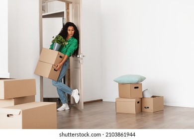 Young Woman Holding Pile Stack Of Cardboard Boxes Walking In Her New House, Busy Female With Full Hands Moving Into Bought Apartment, Opens Door With Leg, Free Copy Space, Full Body Length