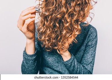 Young Woman Holding Pipette With Nutritional Oil Applying On Her Thick Curly Hair. Female's Hands Using Cosmetic Serum To Prevent Split Ends.