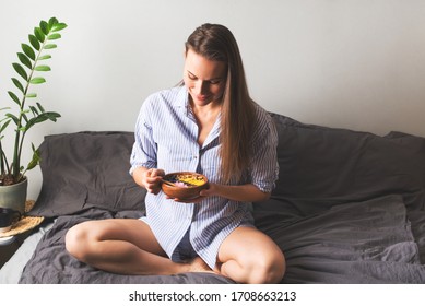 Young Woman Holding A Plate With Smothie Bowl With Fruit And Yogurt, Sitting On Bed, Home Lifestyle, Close Up