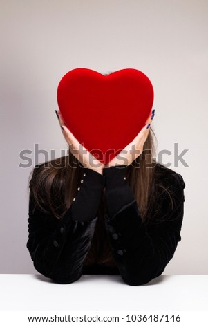Young woman holding a red heart shape