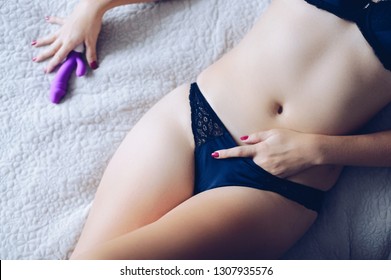 Young woman holding sex toy dildo vibrator in bed