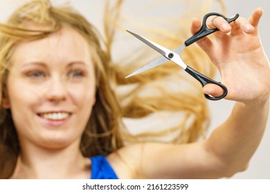 Young woman holding shears tool ready to hair trimming. Blonde female with scissors creating new hairdo coiffure. Hairstyle and haircut.