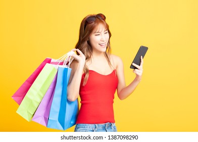 young woman holding shopping bags and smart phone - Shutterstock ID 1387098290