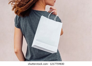 Young Woman Is Holding Shopping Paper Bag On Her Shoulder.