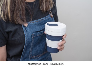 Young Woman Holding A Silicone Collapsible Cup, Reusable Coffee Tumbler.