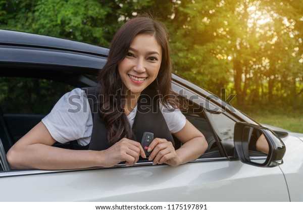 young woman\
holding smart key remote with a\
car