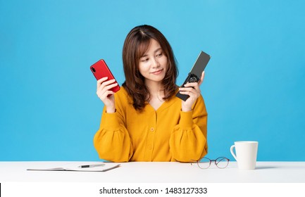 Young woman holding a smart phone and a feature phone.