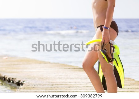 Young woman holding snorkeling at the sea. Slim girl standing on pier at summer tropical vacation. 