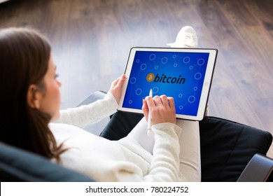 Young woman holding a tablet with cryptocurrency logos - Shutterstock ID 780224752