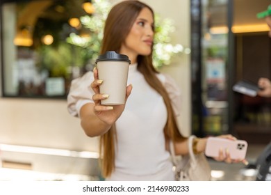 Young woman holding take away carton coffee cup, copy space