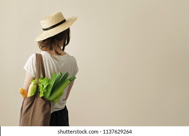 young woman holding textile glocery bag with vegetables 
