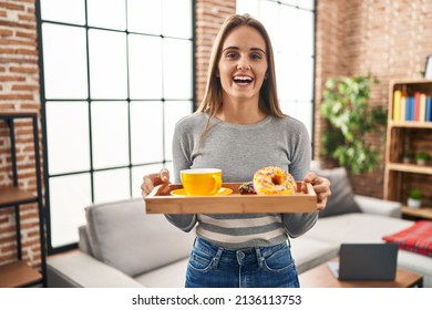 Young woman holding tray with breakfast food smiling and laughing hard out loud because funny crazy joke.  - Powered by Shutterstock