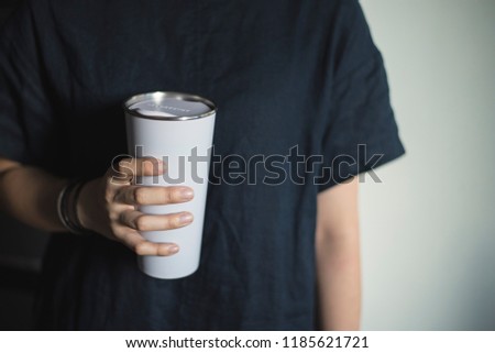 Young woman holding a tumbler, reusable coffee mug/cup in her hands. Stock photo © 