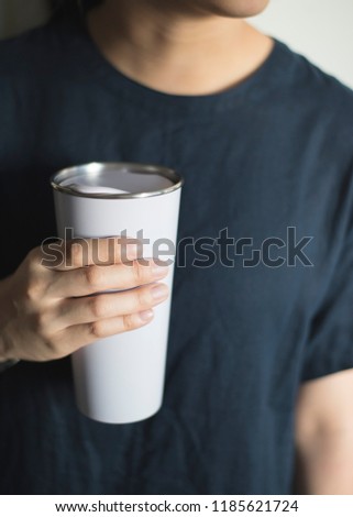 Young woman holding a tumbler, reusable coffee mug/cup in her hands. Stock photo © 