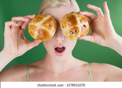 A Young Woman Holding Two Hot Cross Buns In Front Of Her Eyes