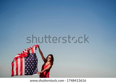 young woman holding United States flag outdoors at sunset. Independence day in America, 4th July concept