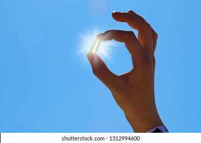 Young Woman Is Holding Vitamin D Capsule. Sun And Blue Sky.