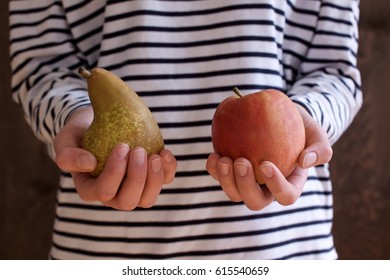 Young Woman Holds An Apple And A Pear In Her Hands