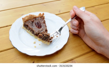 Young woman holds a bite of delicious home-made pecan pie on her fork