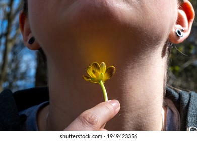 Young Woman Holds A Buttercup Under Her Chin To See If She Likes Butter