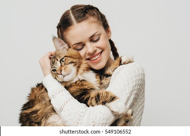 Young Woman Holds In Her Arms And Hugs Maine Coon Cat. White Background