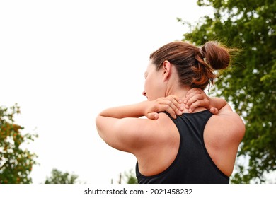 A young woman holds her hands on her neck, doing self-massage, her head is turned to one side, a view from the back, after sports, relaxes her neck, on the way to a healthy and strong body. - Powered by Shutterstock